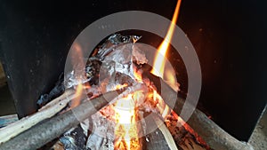 Fire on logs in fire pot with embers and burning coal and blazing flames