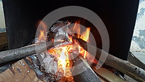 Fire on logs in fire pot with embers and burning coal and blazing flames