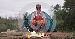Fire, man and camping wood with flames for heating hands and survival in nature with a tent. Adventure, field and rocks