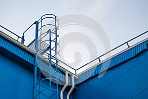 Fire metal staircase on a building metal wall against a blue sky