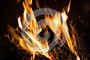 Fire orange tongues on black background in a brick fireplace