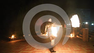 Fire performance. Male artist juggling with burning fire fans at night in the city. Man in black clothes performing a