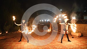 Fire performance at night. Female artists spin burning torch open air on the festival. Fire dancers rotating poles with