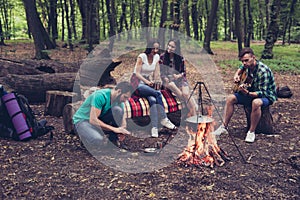 Fire place, four cheerful serene tourists are sitting around