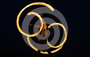 Fire poi artist perform burning reels with glowing, tails in motion on dark sky outdoors, stunt