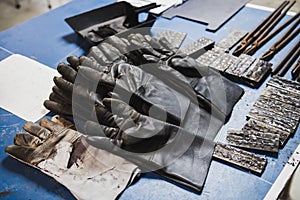 Fire Protection gloves, pliers and many pieces of steel on the desk to be used in electric metal welding workshop.