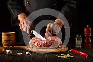 For fire, raw meat must be cut into small pieces. Hands of a chef with a knife in the kitchen. Cooking delicious food for a