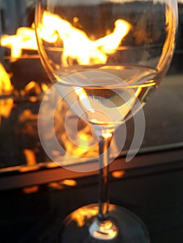 Fire refection in background glass of wine by fireside.