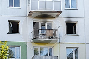 Fire in a residential, apartment building. Opened, broken windows of a burnt-out apartment, soot on the facade of the building