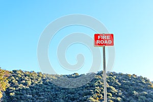 Fire Road Sign Against Blue Sky and Dense Forest
