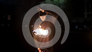 The fire show artist spins two linked fireballs around his axis. dangerous trick