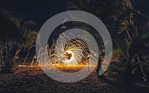 Fire show at the beach at night performing a fire wheel