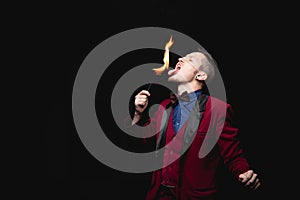 Fire show, fakir magician swallows burn and puts out tongue in mouth