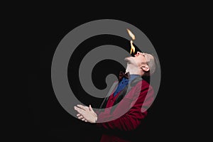 Fire show, fakir magician swallows burn and puts out tongue in mouth