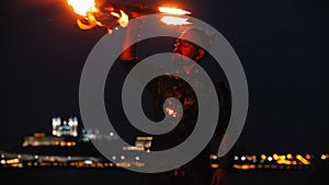 Fire show - a man dancing with a fire torch on the night beach
