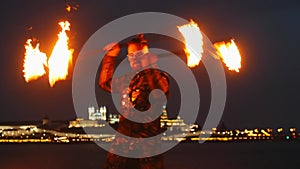 Fire show - a man dancing with two fire torches on the night beach