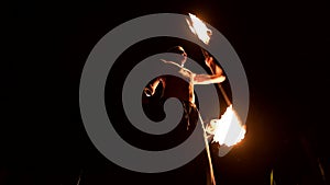 Fire show. Man juggles with two burning torches. Night show. Mastery of the fakir. Low angle