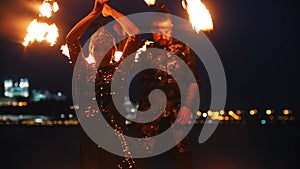 Fire show performance - man and woman in a shiny dress playing with fire on the beach