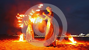 Fire show - two women in shiny dresses lighting up their torches and start dancing