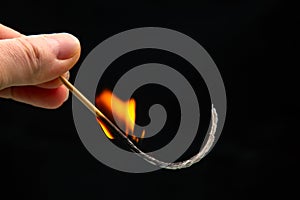 Fire and smoke. Burning match in hand on a black background. Heat and light from fire flame