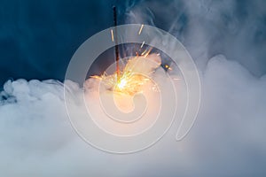 Fire sparkler in dense smoke, abstract Christmas firework background