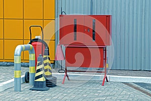 Fire stand from a red metal box and a set of tools stands on a gray sidewalk