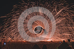 Fire steel wool with water reflection on sea in beach club party at night Samui Thailand