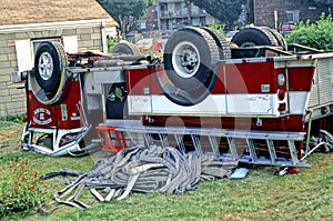 A fire truck sits upside down on a front lawn