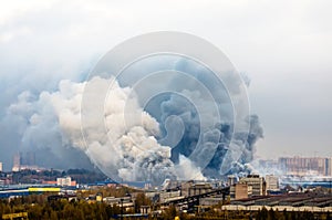 Fire in warehouses with dark and white huge smoke clouds.