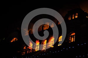 Fire in the windows of the old building at night in winter against the background of garlands. fire extinguishing. Kiev, January