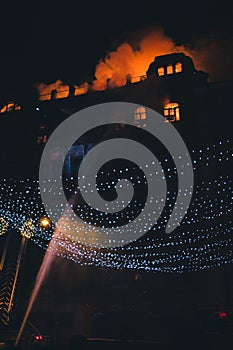 Fire in the windows of the old building at night in winter against the background of garlands. fire extinguishing. Kiev, January