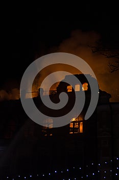 Fire in the windows of the old building at night in winter against the background of garlands. fire extinguishing. Kiev, January