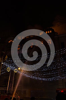 Fire in the windows of the old building at night in winter against the background of garlands. fire extinguishing. Kiev, January