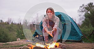 Fire, woman and camping wood with flames for heating hands and eco holiday in nature with a tent. Adventure, field and