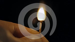 Fire of a wooden match in complete darkness, disappears from the flame on a black background, lighting and burning until
