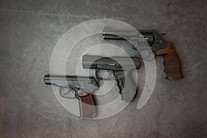 Firearms laid out along the line. Three guns close-up on a gray concrete background.  copy space