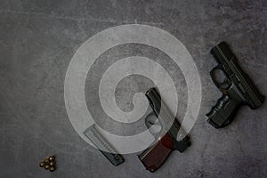 Firearms laid out along the line. Three guns pistols, cartridges close-up on a gray concrete background. copy space