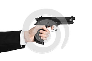 Firearms and security topic: a man in a black suit holding a gun on an isolated white background in studio