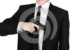 Firearms and security topic: a man in a black suit holding a gun on an isolated white background in studio