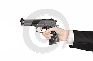 Firearms and security topic: a man in a black suit holding a gun on an white background in studio