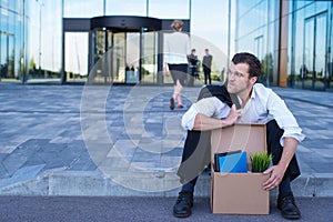 Fired businessman sitting on street