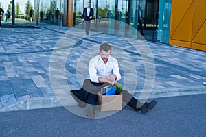 Fired businessman sitting on street