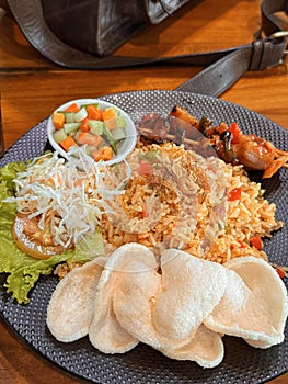 Fired rice or nasi goreng Indonesian chicken fried rice served with pickled cucumber and onion and chili with prawn crackers with