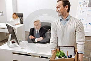 Fired smiling employee carrying the box and quitting the job