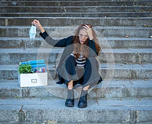 Fired woman on stairs holding face mask. conceptual image of Coronavirus job cuts and unemployment