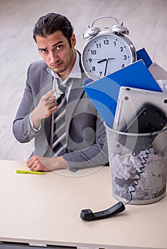 Fired young businessman with recycle bin in time management conc