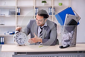 Fired young businessman with recycle bin in time management conc