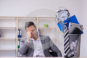 Fired young businessman with recycle bin in time management conc