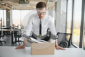 Fired young man packing his stuff in office