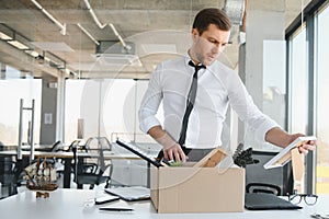 Fired young man packing his stuff in office